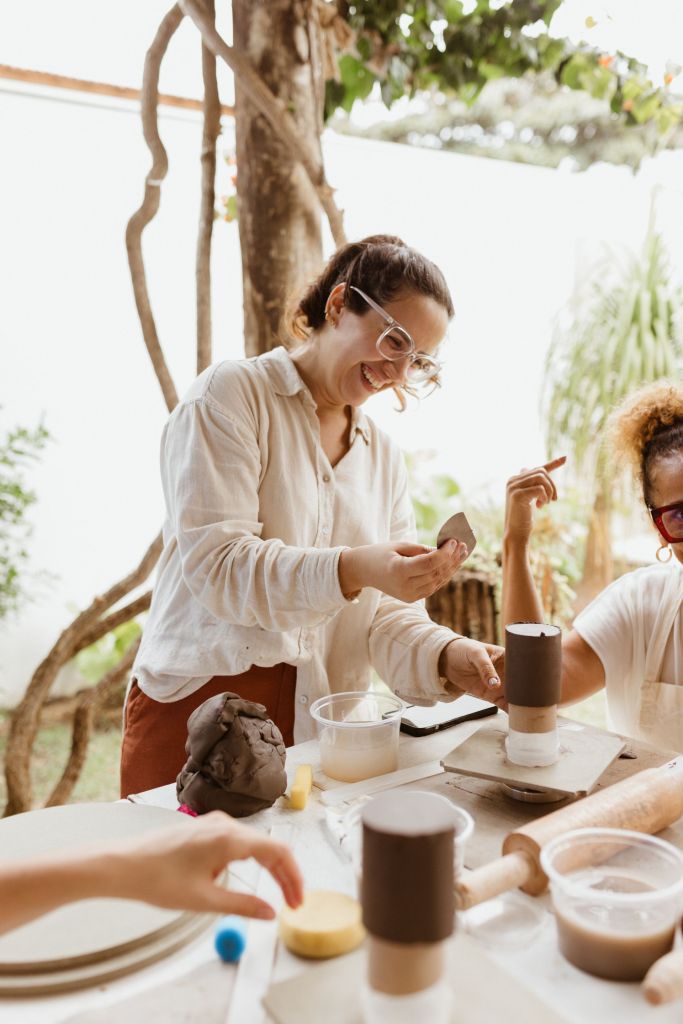 Friends laughing together during a bright outdoor pottery class