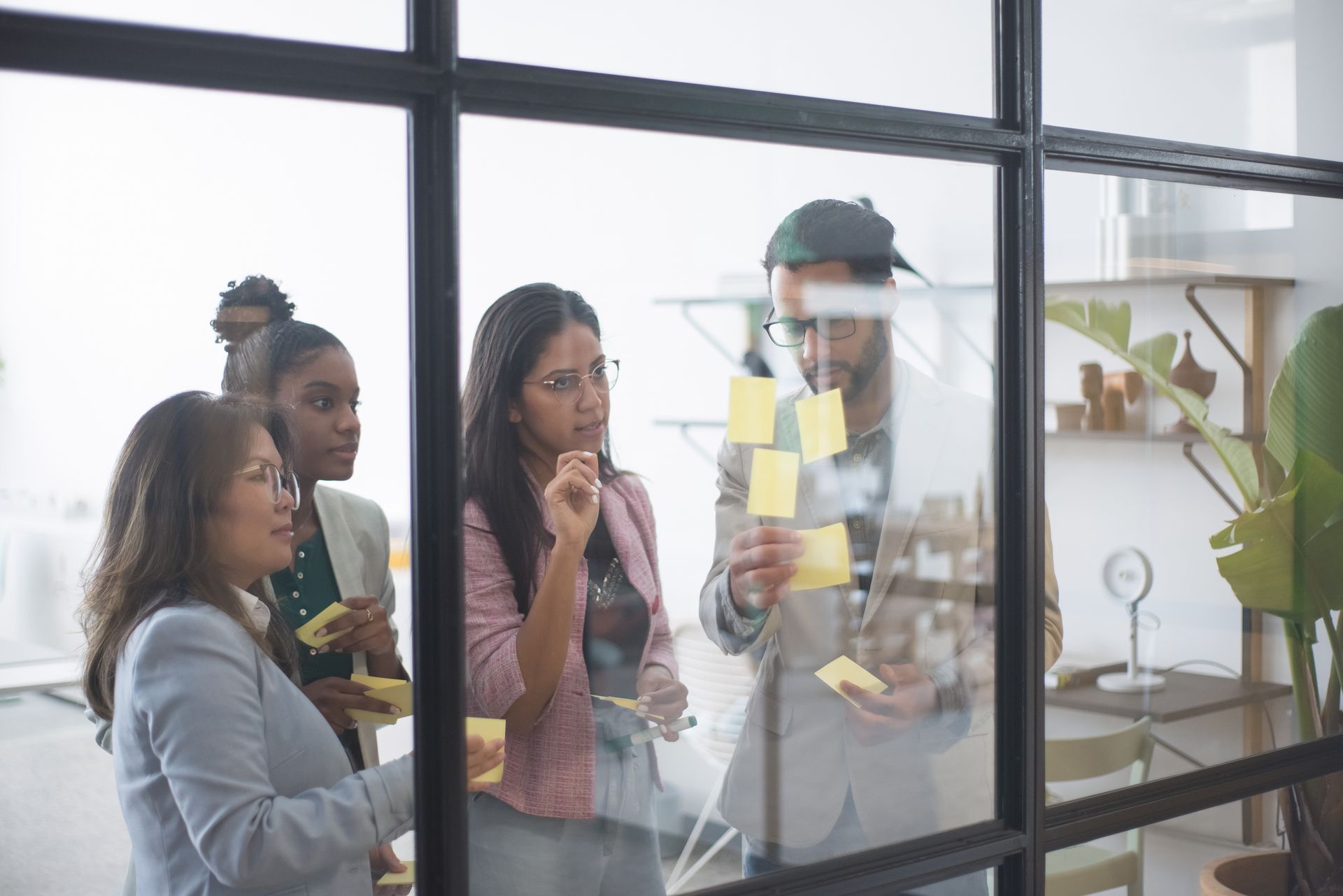 Business leaders brainstorming with sticky notes on a glass wall during a team workshop